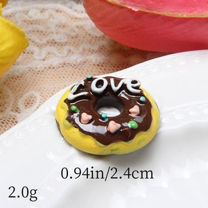Macro detail of a resin doughnut charm with chocolate coating and LOVE text on a plate