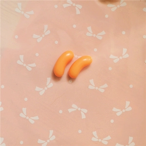 Detalle macro de dos colgantes de resina naranja para decorar fundas de móvil artesanales