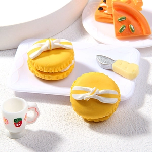 Détail macro de breloques macarons jaunes en pâte polymère avec nœud et accessoires miniatures