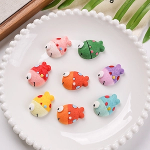 Macro detail of eight colorful resin fish charms with matte texture on a white plate
