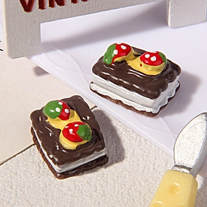 Dettaglio di ciondoli in resina a forma di biscotto al cioccolato e fragola
