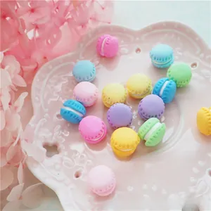 Detailed view of colorful clay macaron charms for DIY phone cases on a pink plate