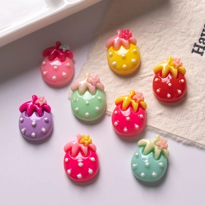 Close-up of colorful resin strawberry charms with polka dots and small flowers for DIY crafts