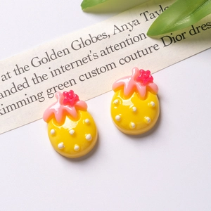 Flat lay of yellow resin strawberry DIY charms with white polka dots for hair accessories
