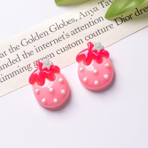 Detailed view of pink resin strawberry charms with white dots for DIY hair accessories