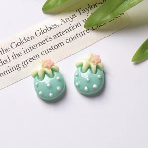 Detailed view of mint green resin strawberry charms with white dots for DIY crafts