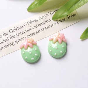 Close-up of resin strawberry charms with white dots and pink leaves for DIY crafts