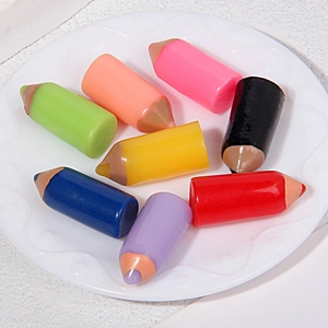 Close-up of eight colorful miniature resin pencils on a white decorative ceramic plate