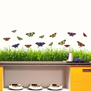 Détail de stickers muraux papillons colorés avec motifs d'herbe sur un mur blanc
