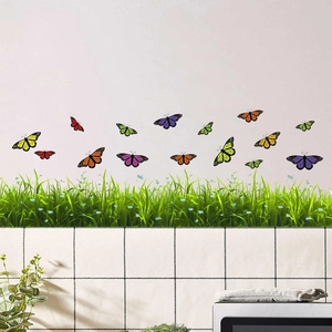 Détail de stickers muraux imperméables papillons et herbe sur un mur blanc de salon