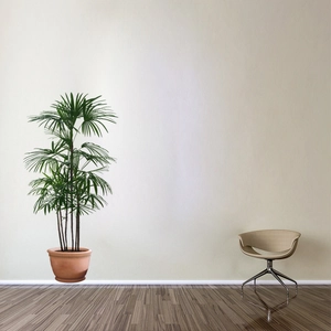 Green palm plant in red clay pot next to a modern beige swivel chair on wood floor
