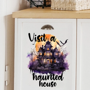Watercolor haunted house sticker with pumpkins on a white kitchen cabinet for Halloween