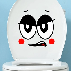 Close-up of funny cartoon facial expression sticker on a white toilet lid in a bathroom