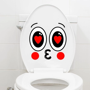 Close-up of creative cartoon face sticker with heart eyes on a white toilet lid cover