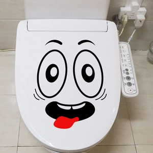 Close-up of funny cartoon face sticker with tongue out on a white toilet seat cover