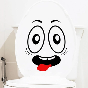 Close-up of funny smiley face wall sticker with big eyes and red tongue on white toilet lid