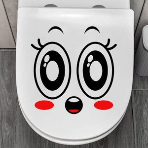 Close-up of a funny surprised face sticker on a white toilet lid in a home bathroom setting