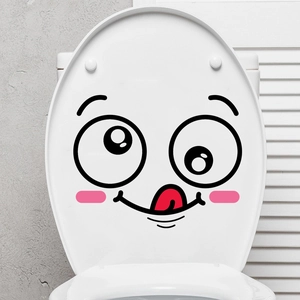 Funny cartoon face decal with pink cheeks and tongue-out smile on a white toilet lid