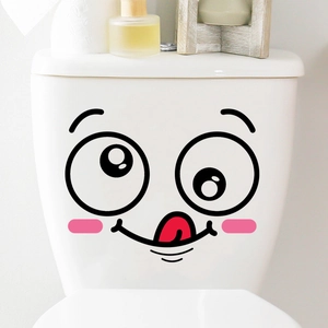 Detail of cute smiley face decal with tongue out on a white ceramic toilet tank