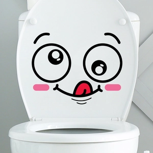 Funny cartoon face wall sticker with pink cheeks and red tongue on white toilet lid