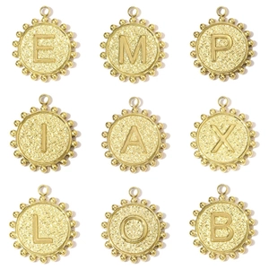 Macro view of gold round letter pendants with hammered metal texture and beaded edges