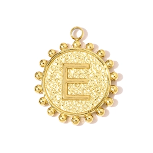 Detail of round gold pendant with hammered texture and engraved letter E on white background