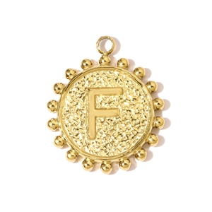 Detail of round golden pendant with embossed letter F and textured hammered finish