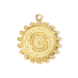 Macro view of golden letter G pendant with hammered texture and beaded border