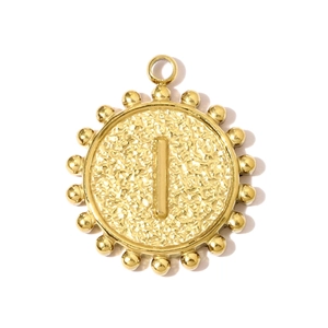 Macro detail of a golden round pendant featuring a 3D letter I and hammered texture