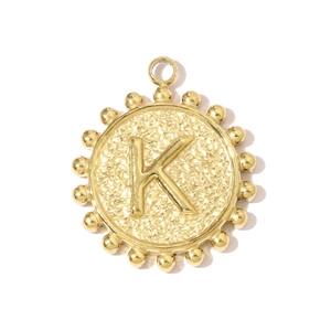 Macro detail of vintage gold-plated square pendant with hammered texture and letter K