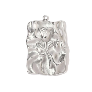 Close-up of a silver stainless steel rectangular pendant with a raised rose flower relief