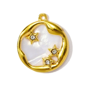 Vue macro d'un pendentif en nacre et acier doré orné d'étoiles et de zircons