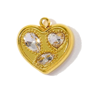 Gros plan d'un pendentif cœur doré avec trois zircons clairs incrustés et un anneau de bélière