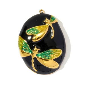 Detailed macro of oval black enamel pendant with golden dragonflies and green wings