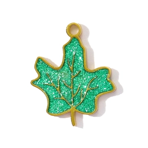 Detail of green maple leaf charm with glitter inlay and gold stainless steel edges