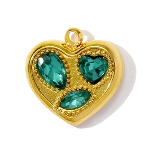 Détail macro du pendentif cœur doré orné de trois pierres incrustées vert foncé