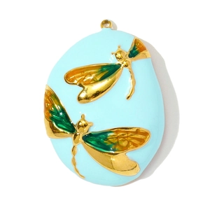 Detailed macro view of oval gold pendant with light blue enamel and dragonfly motif