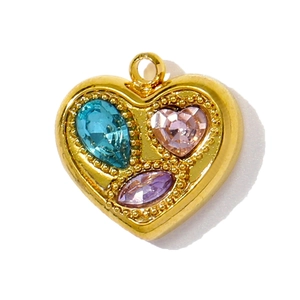 Détail d'un pendentif cœur doré avec des pierres précieuses bleues, roses et violettes