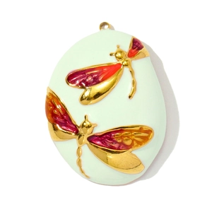 Macro detail of oval dragonfly pendant with mint green enamel and gold finish
