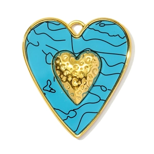 Detail of a gold heart pendant with turquoise resin inlay and hammered metal heart