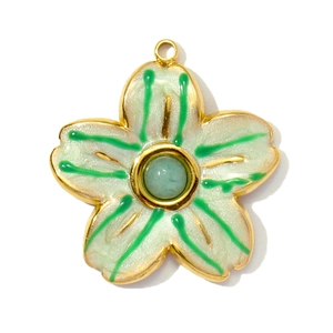 Detail view of flower pendant with white petals and green stone in gold setting
