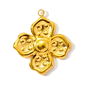 Détail d'un pendentif fleur dorée à quatre pétales avec points en relief et dôme central