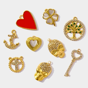 Flat lay of gold-plated stainless steel charms including heart, skull, and tree of life