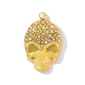 Detail of a golden skull pendant with sparkling rhinestones on a white background