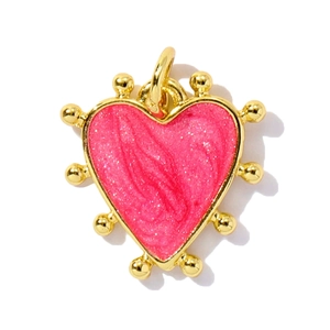 Macro detail of heart-shaped pink enamel pendant with golden beads and metallic rim
