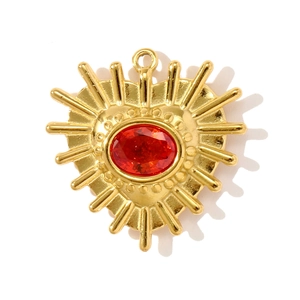 Detalle de un colgante de corazón dorado con gema roja y diseño de rayos de sol