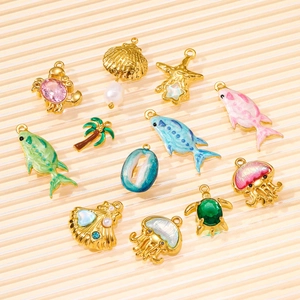 Detailed close-up of 12 gold plated ocean themed charms with enamel and pearls