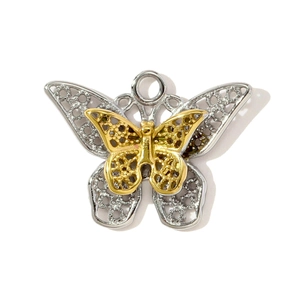 Détail macro d'un pendentif papillon bicolore or et argent avec motifs ajourés