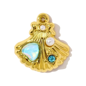 Detailed close-up of a golden scallop charm with pearls and blue gemstone accents