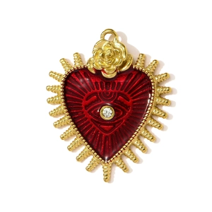 Detail of a vintage gold heart pendant with red enamel, rose flower, and an evil eye charm